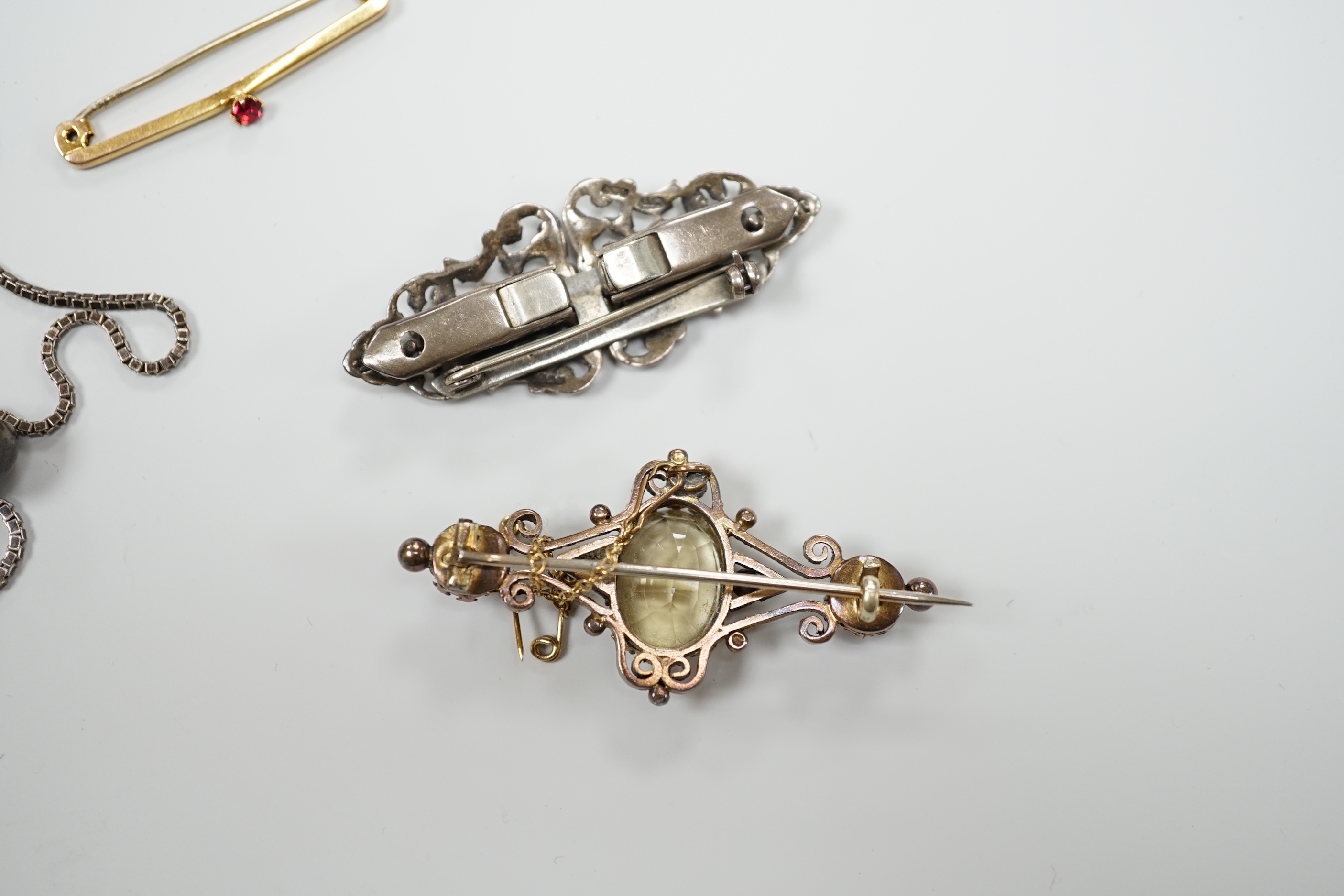 A white metal oval locket on chain, a white metal and marcasite clip brooch, a yellow metal and three stone amethyst and citrine set brooch and a 9ct and gem set brooch.